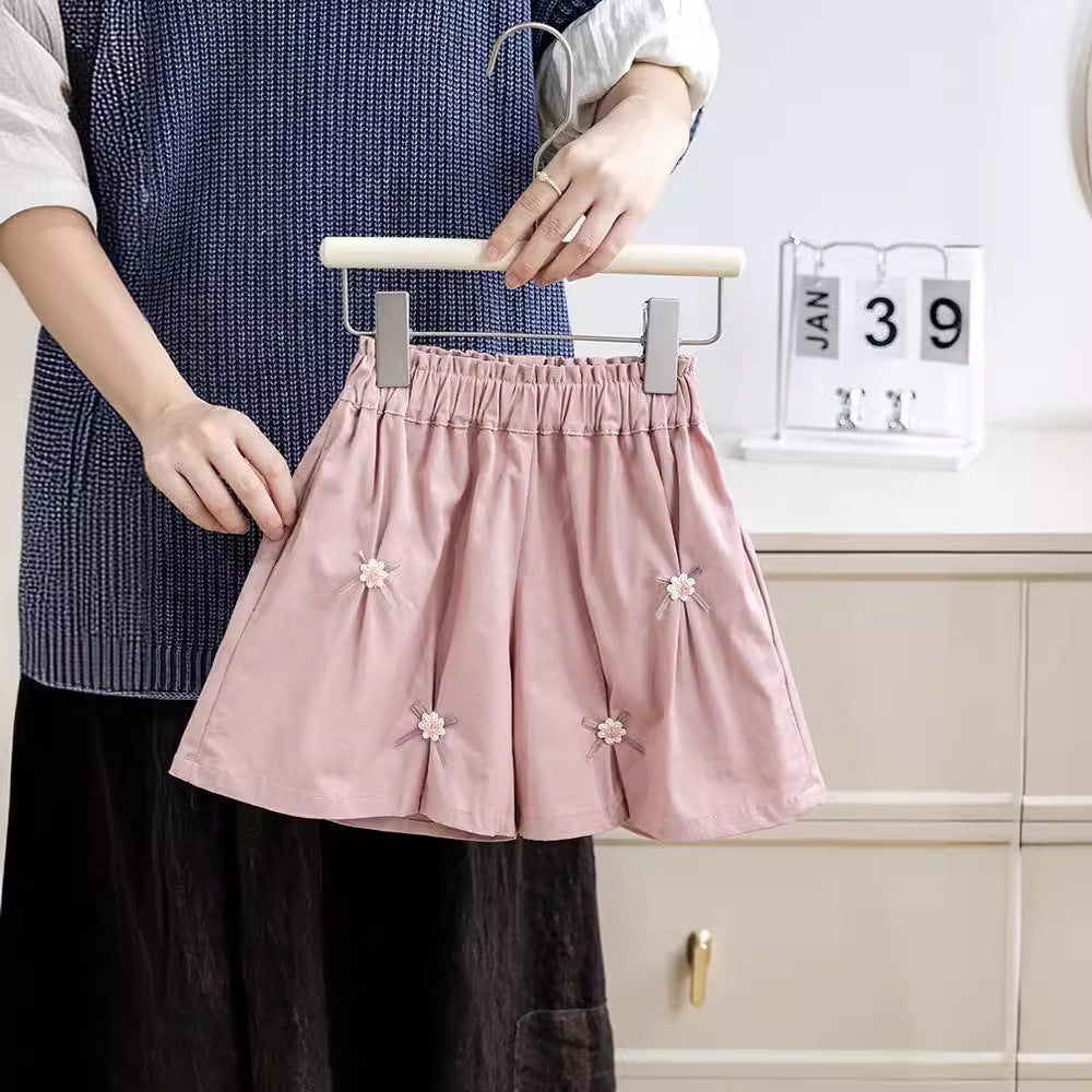 A cute summer pleated skirt for girls featuring a floral pattern and bows, available in pink and coffee colors.