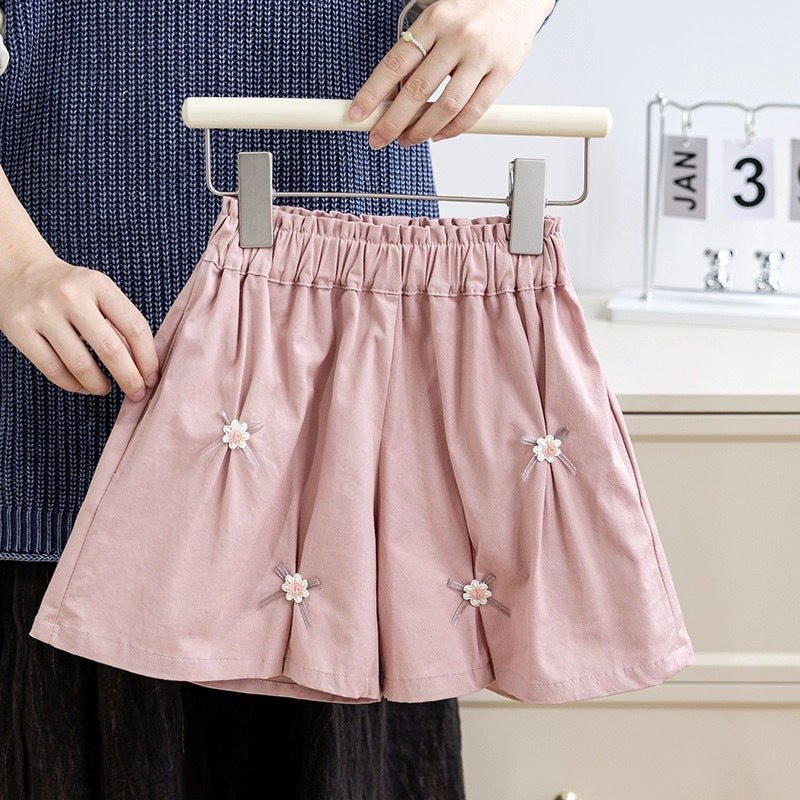 A cute summer pleated skirt for girls featuring a floral pattern and bows, available in pink and coffee colors.