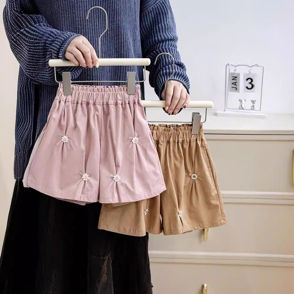 A cute summer pleated skirt for girls featuring a floral pattern and bows, available in pink and coffee colors.