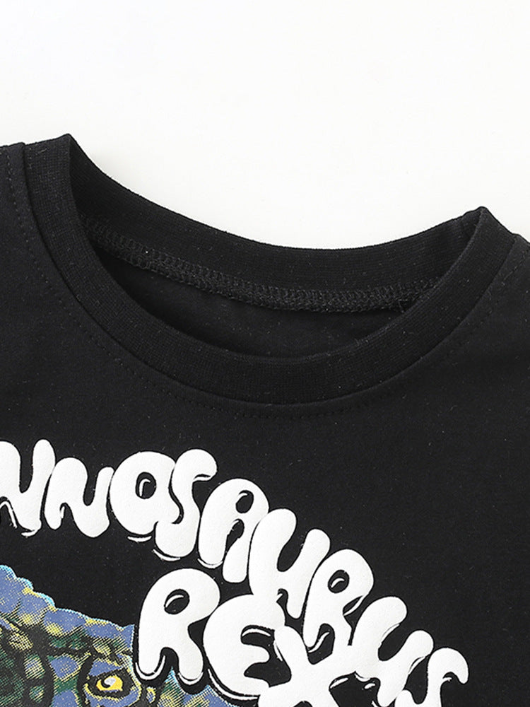 A black short-sleeved t-shirt featuring a fierce cartoon dinosaur print, designed for boys aged 12 months to 10 years.