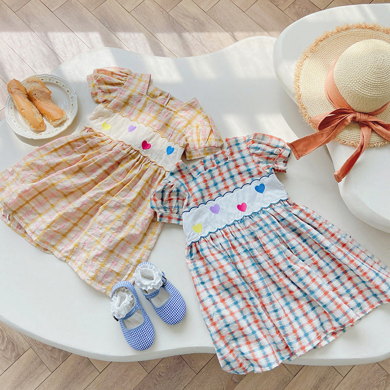 A colorful plaid dress for girls featuring short sleeves and heart embroidery, perfect for summer outings.