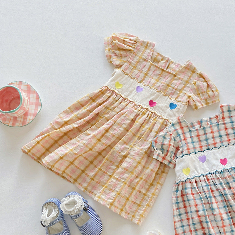 A colorful plaid dress for girls featuring short sleeves and heart embroidery, perfect for summer outings.