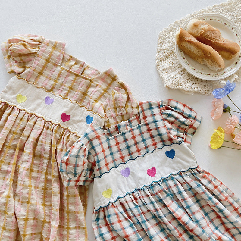 A colorful plaid dress for girls featuring short sleeves and heart embroidery, perfect for summer outings.