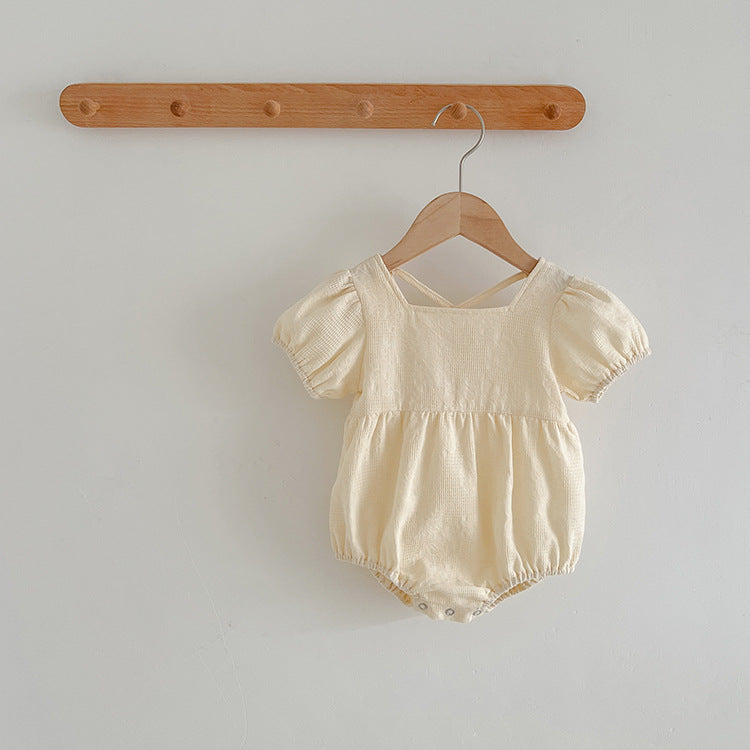 A stylish summer onesie for girls in beige and apricot colors, featuring a simple square neck design, made from soft cotton and polyester.