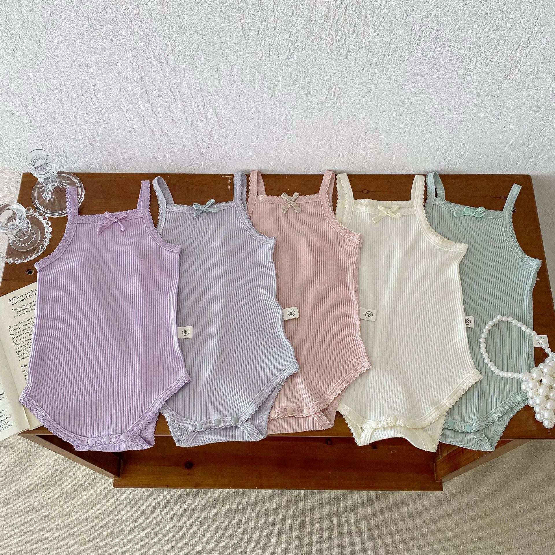 A collection of soft cotton baby girls onesies in solid colors: pink, purple, green, grey, and beige, perfect for summer wear.