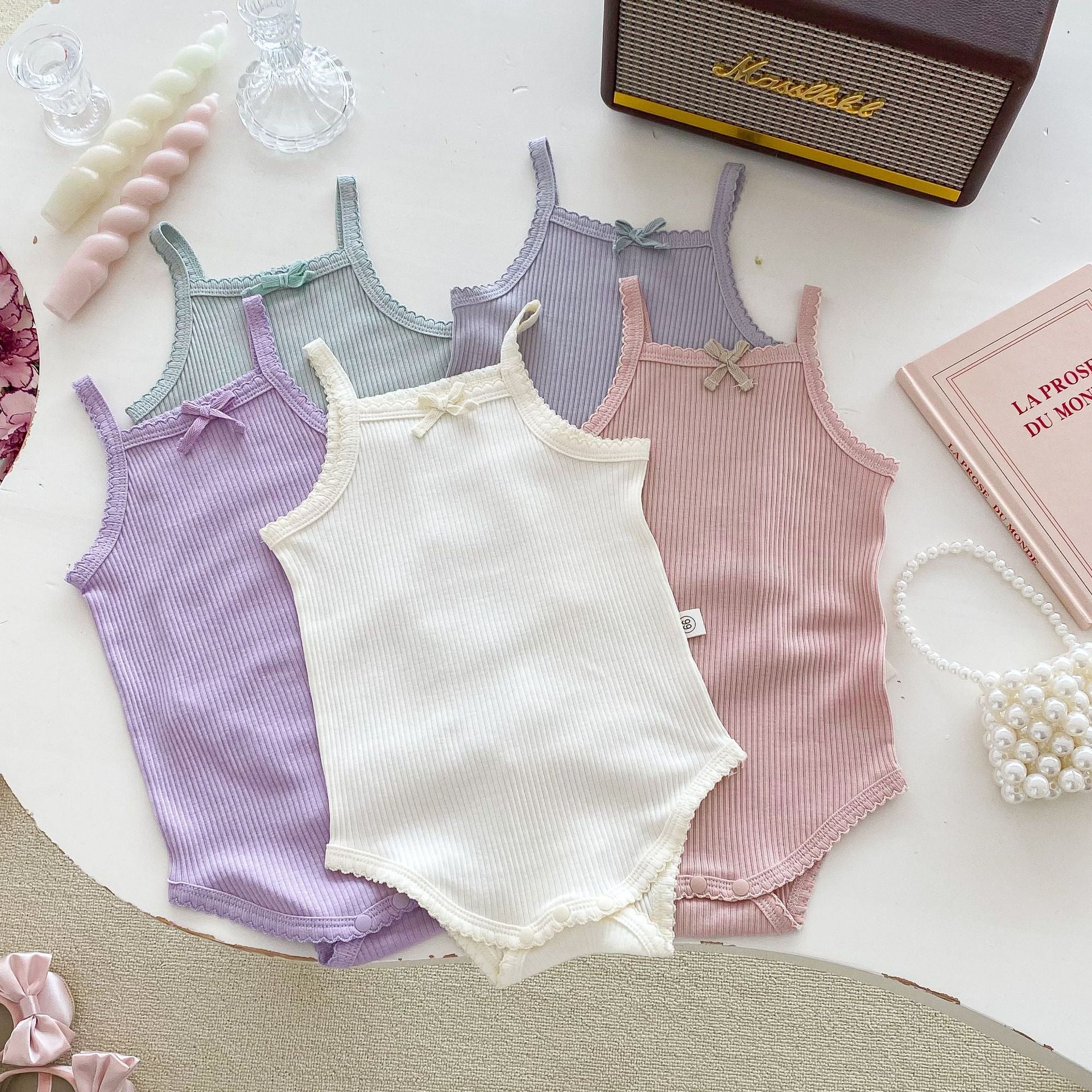 A collection of soft cotton baby girls onesies in solid colors: pink, purple, green, grey, and beige, perfect for summer wear.