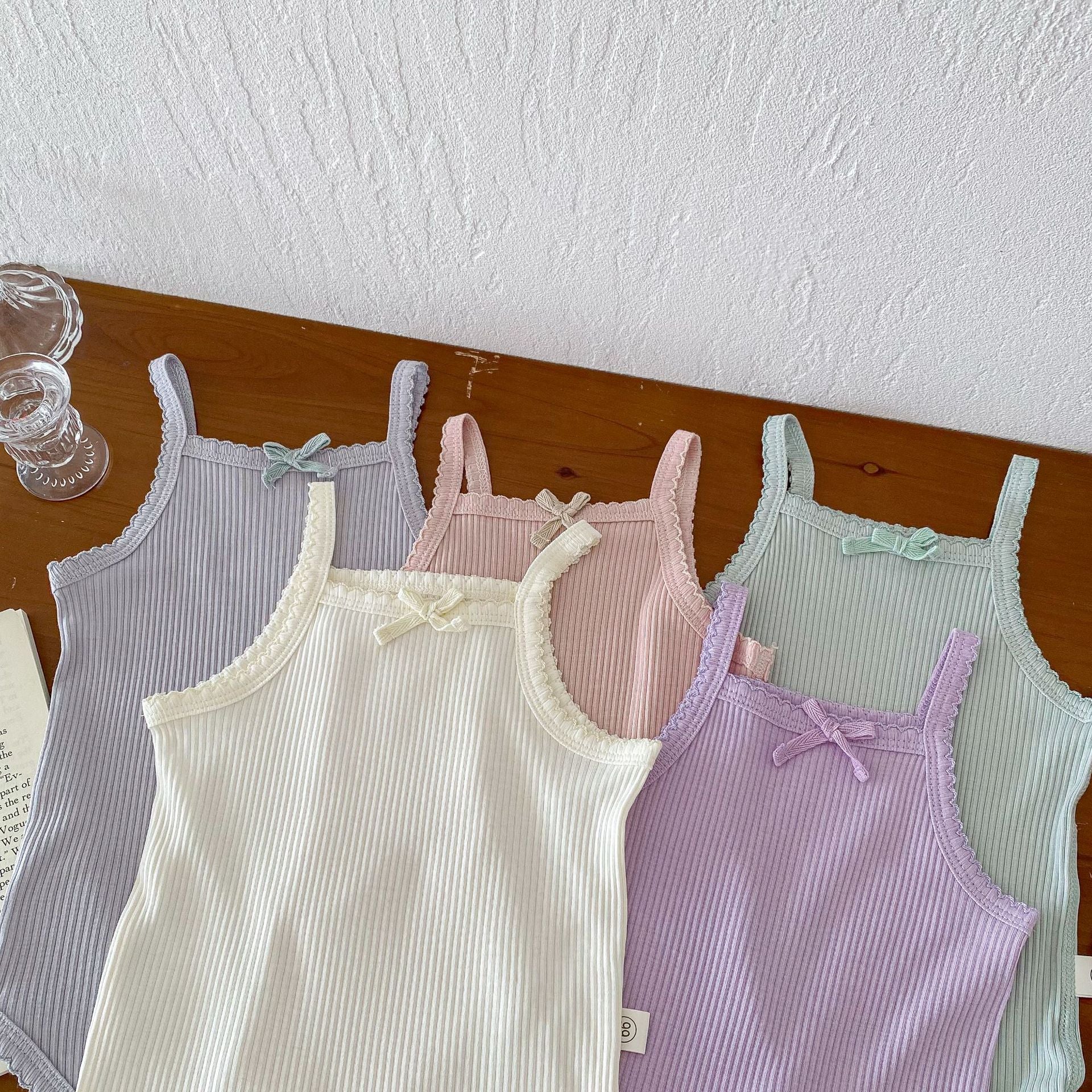 A collection of soft cotton baby girls onesies in solid colors: pink, purple, green, grey, and beige, perfect for summer wear.