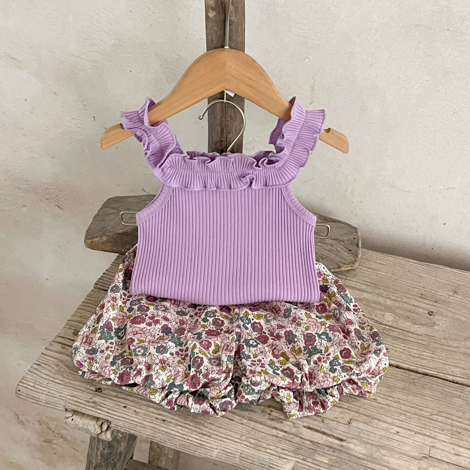 A collection of baby girls' sleeveless solid color strap tops in pink, purple, green, and beige, made from soft cotton fabric.