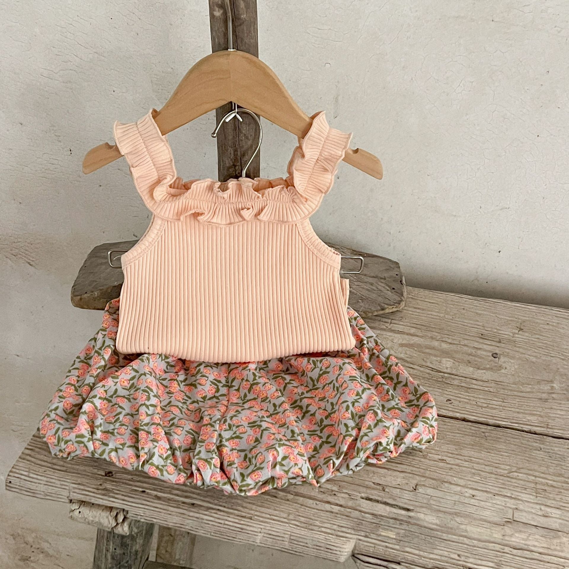 A collection of baby girls' sleeveless solid color strap tops in pink, purple, green, and beige, made from soft cotton fabric.