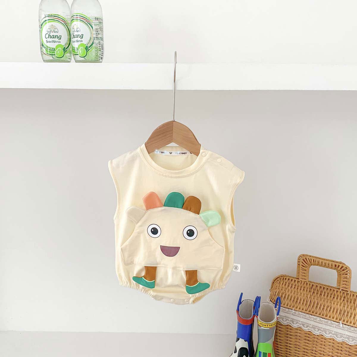 A beige sleeveless crew neck top for babies, made of thin cotton with a cartoon pattern, suitable for summer wear.