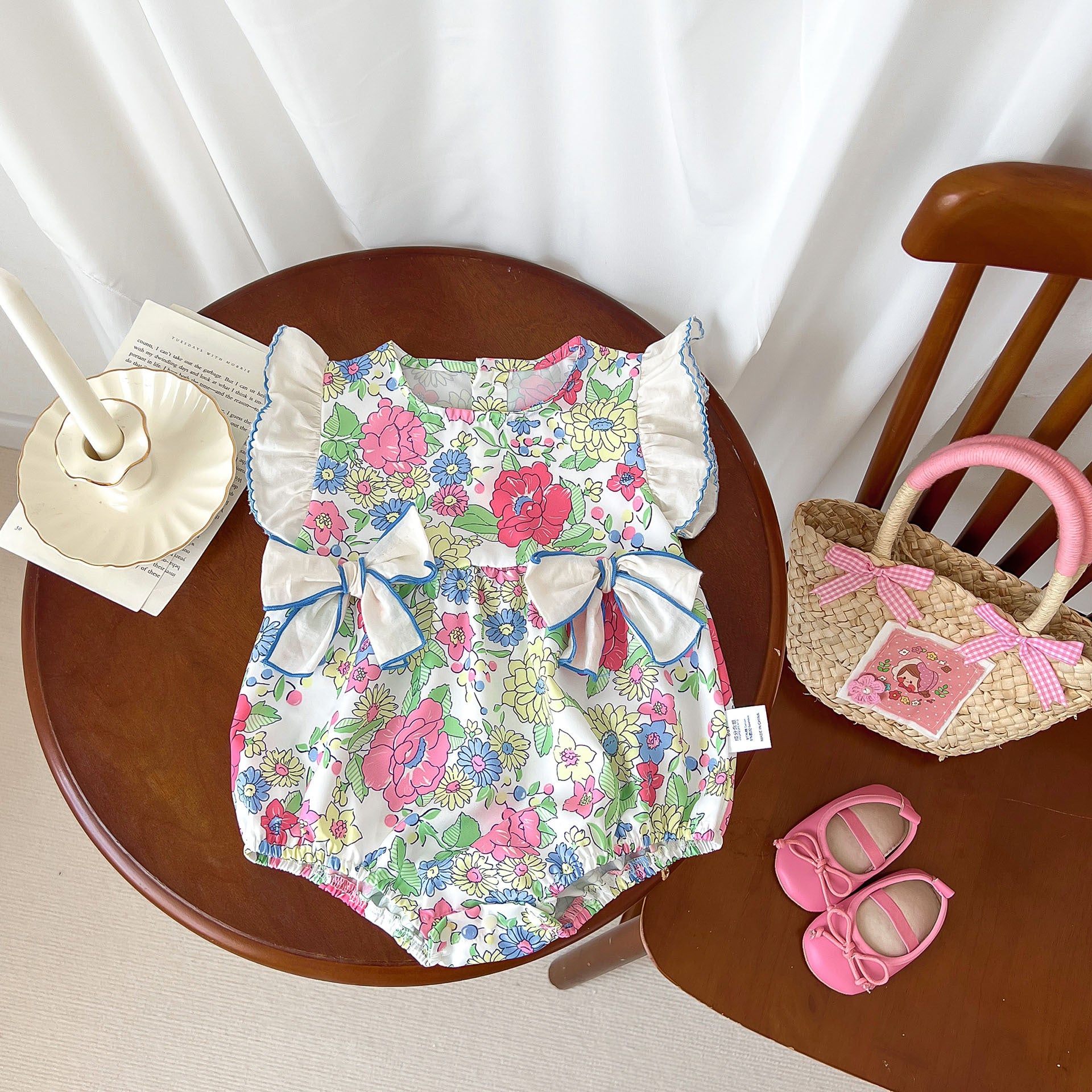 Baby girl wearing a blue floral dress with fly sleeves and 3D bows, perfect for summer.