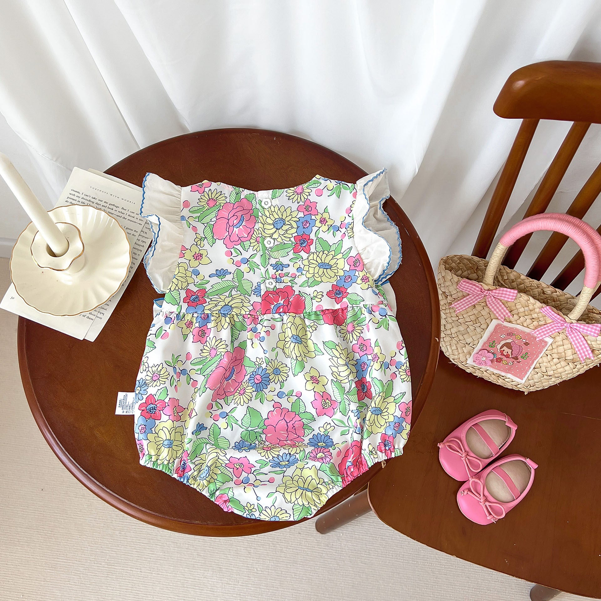 Baby girl wearing a blue floral dress with fly sleeves and 3D bows, perfect for summer.