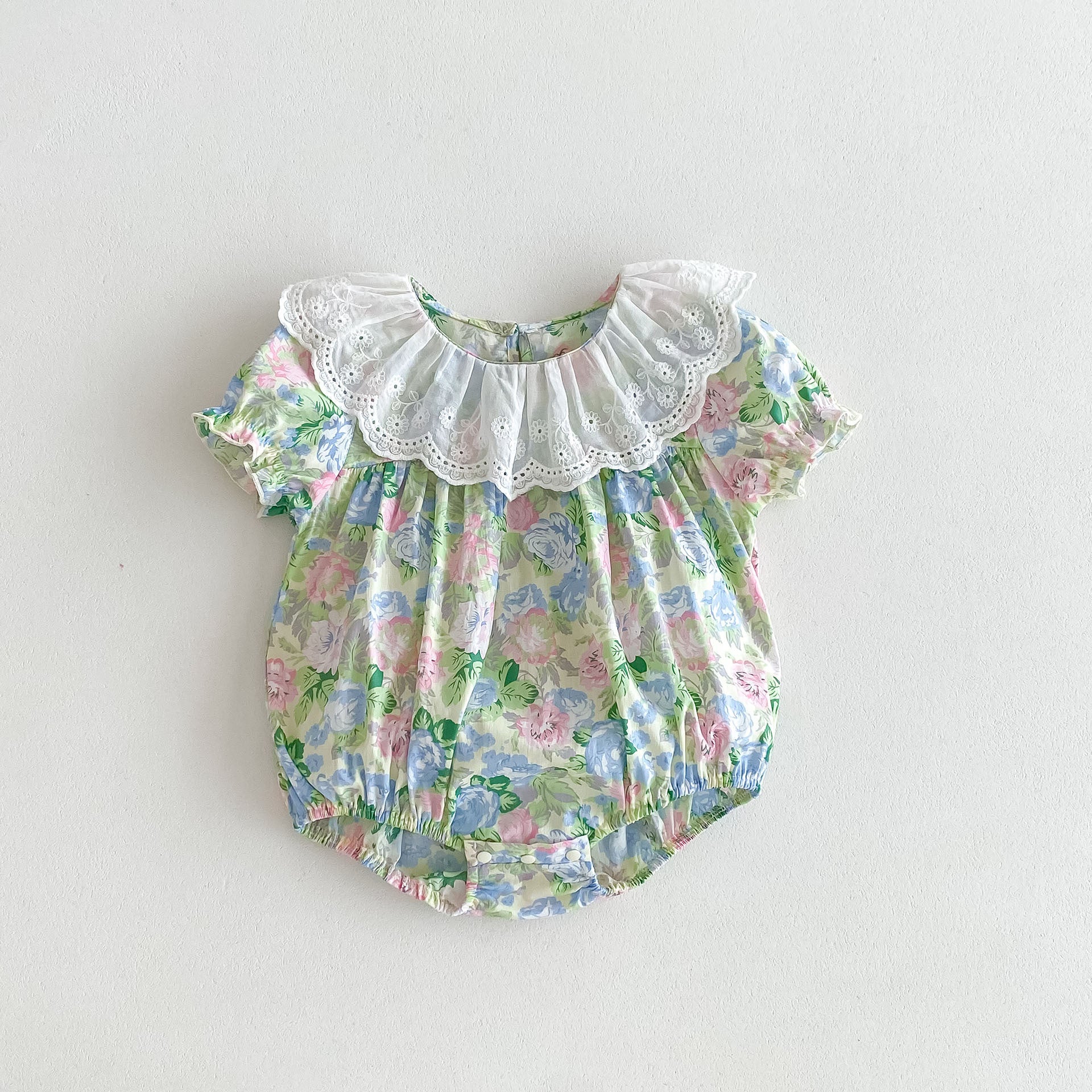 A cute baby girl wearing a floral print dress with short sleeves and a ruffle collar, perfect for summer outings.