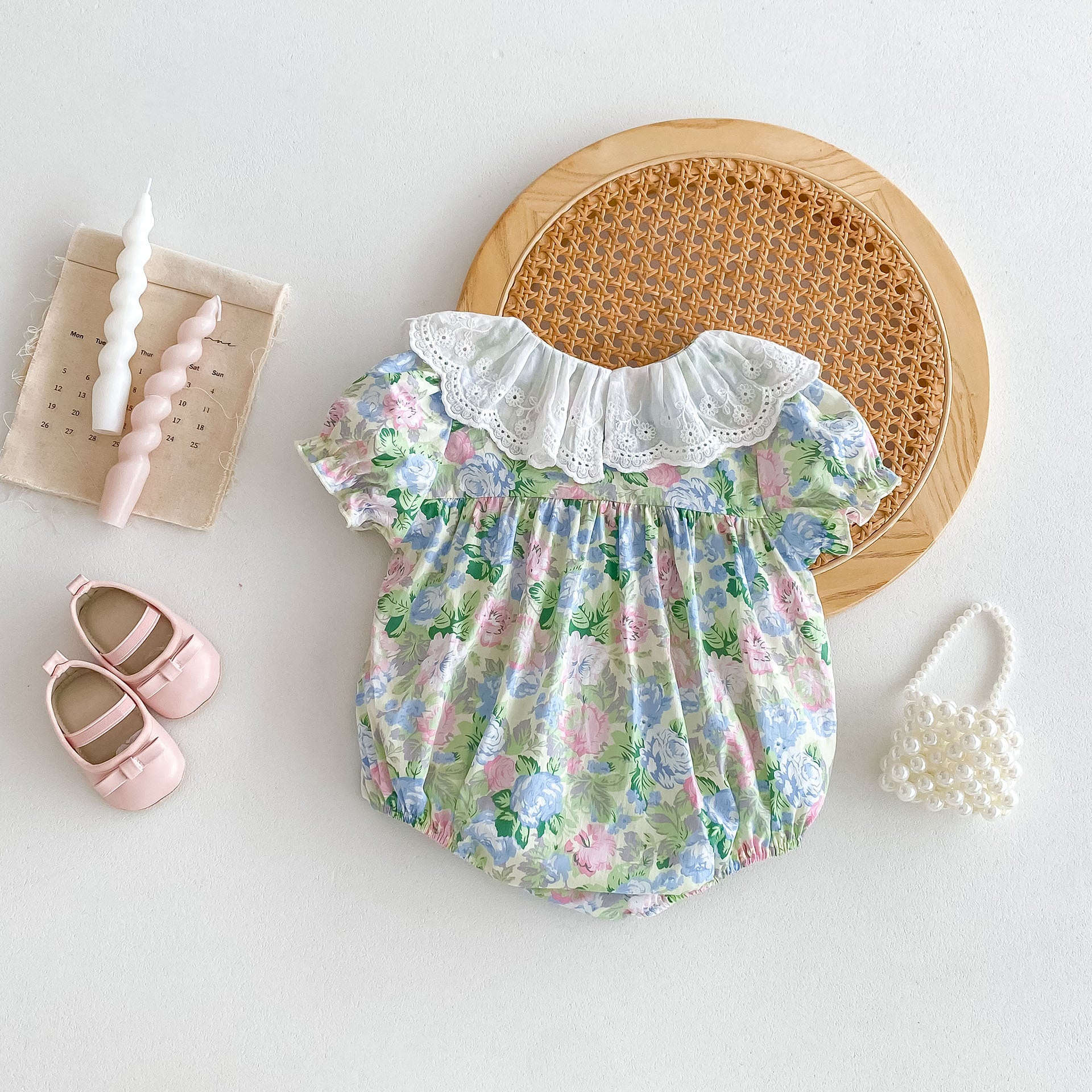 A cute baby girl wearing a floral print dress with short sleeves and a ruffle collar, perfect for summer outings.