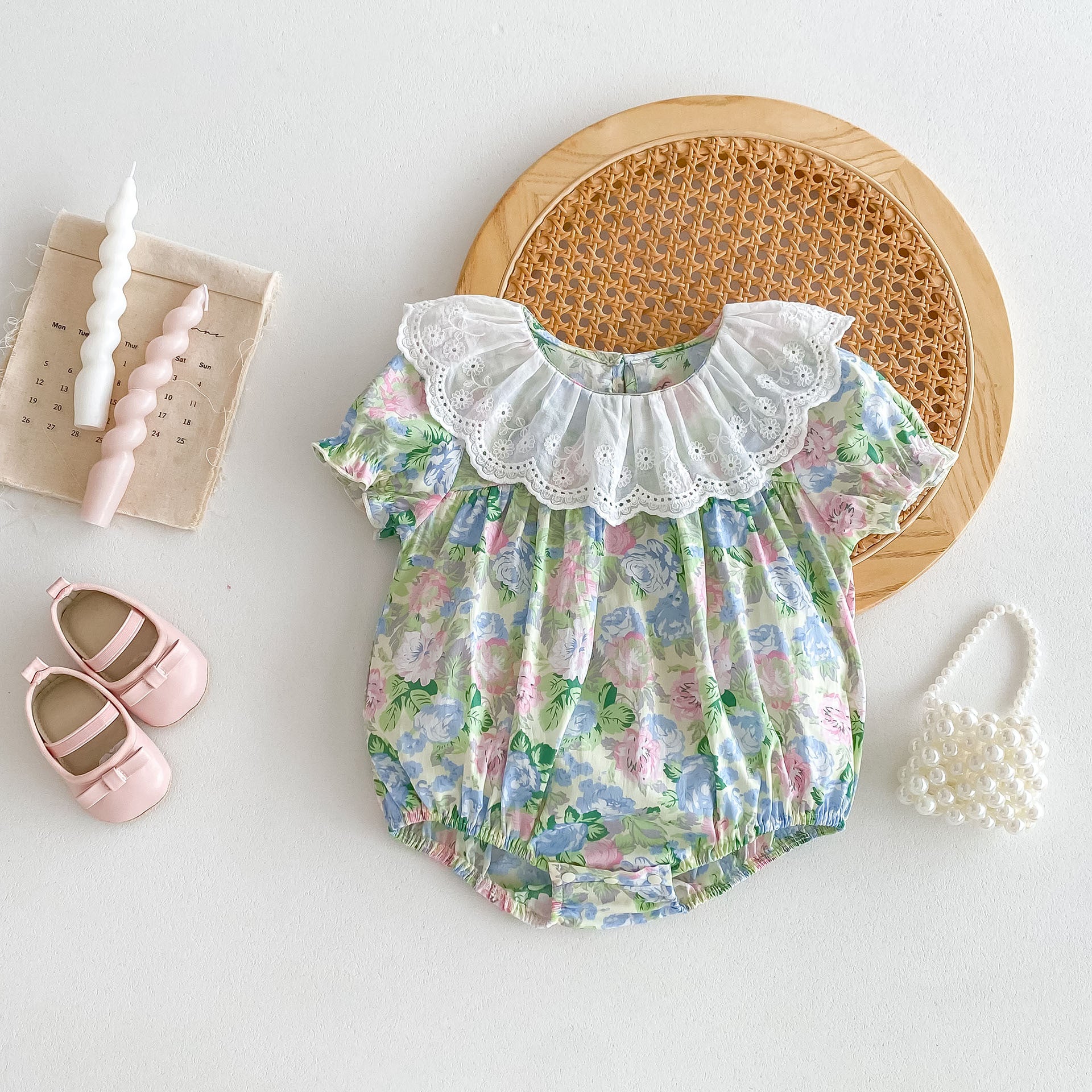 A cute baby girl wearing a floral print dress with short sleeves and a ruffle collar, perfect for summer outings.