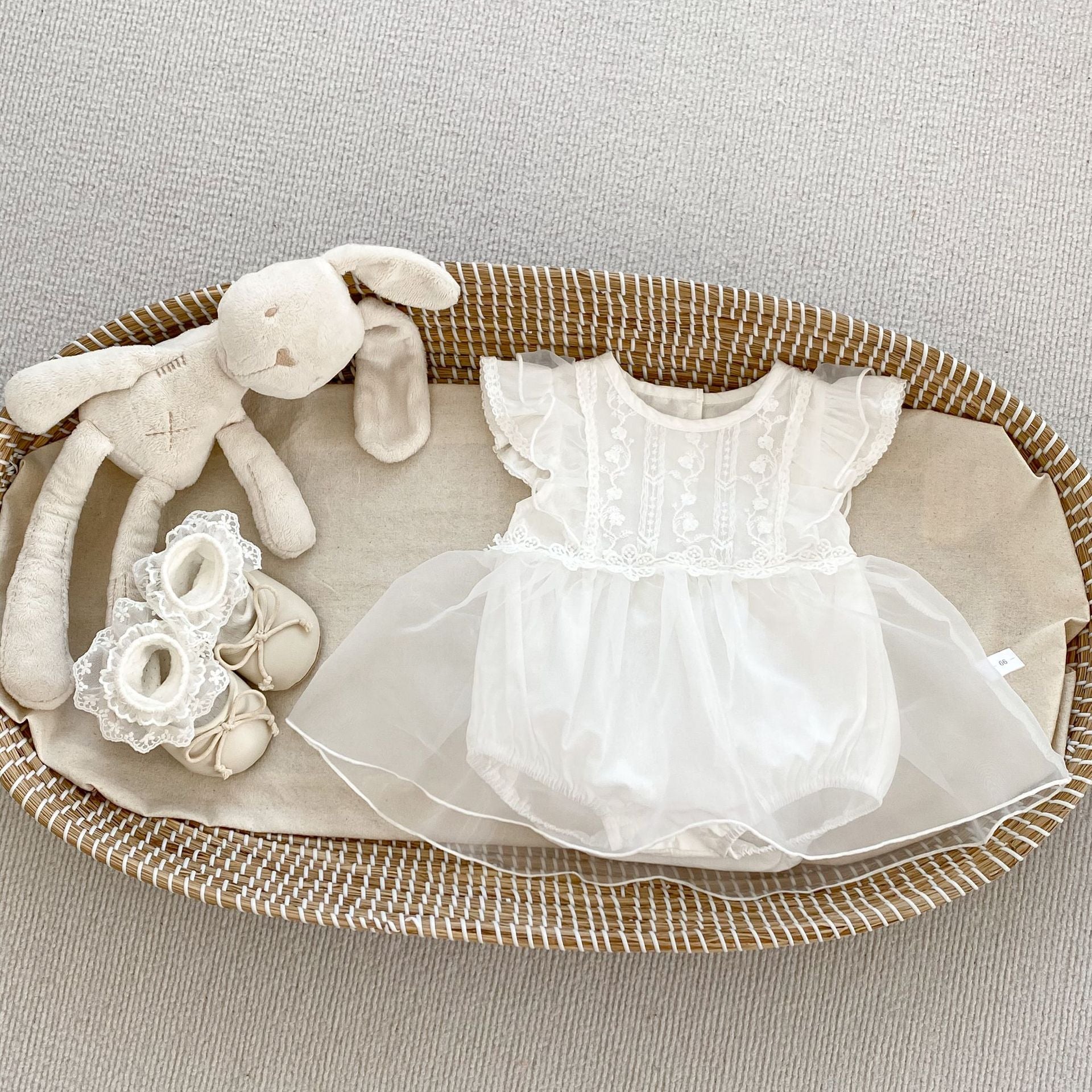 A cute baby girl wearing a white flower-embroidered crew neck top with fly sleeves, perfect for summer.