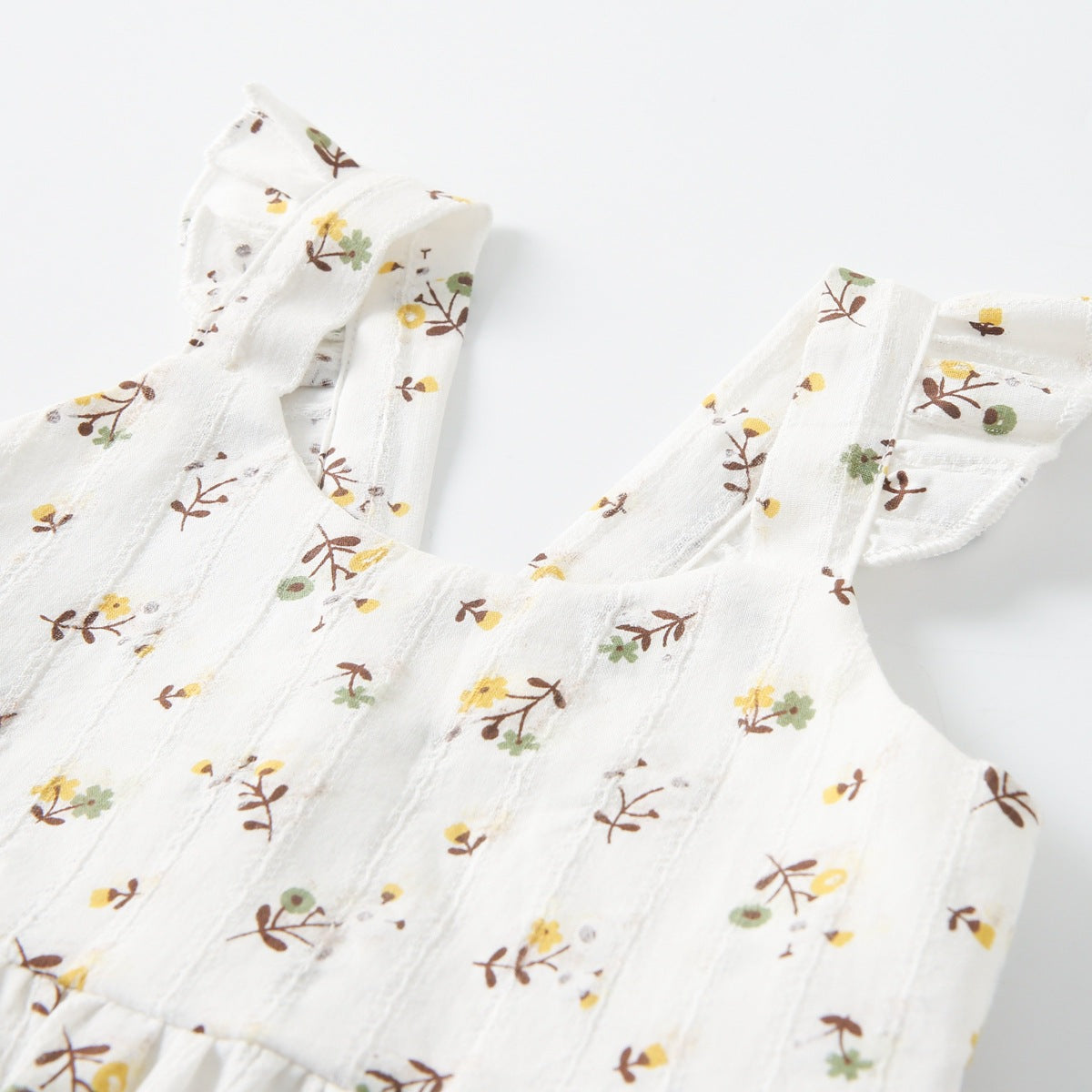 A beautiful baby girls' summer dress featuring a floral pattern and princess straps in white, yellow, and apricot colors.