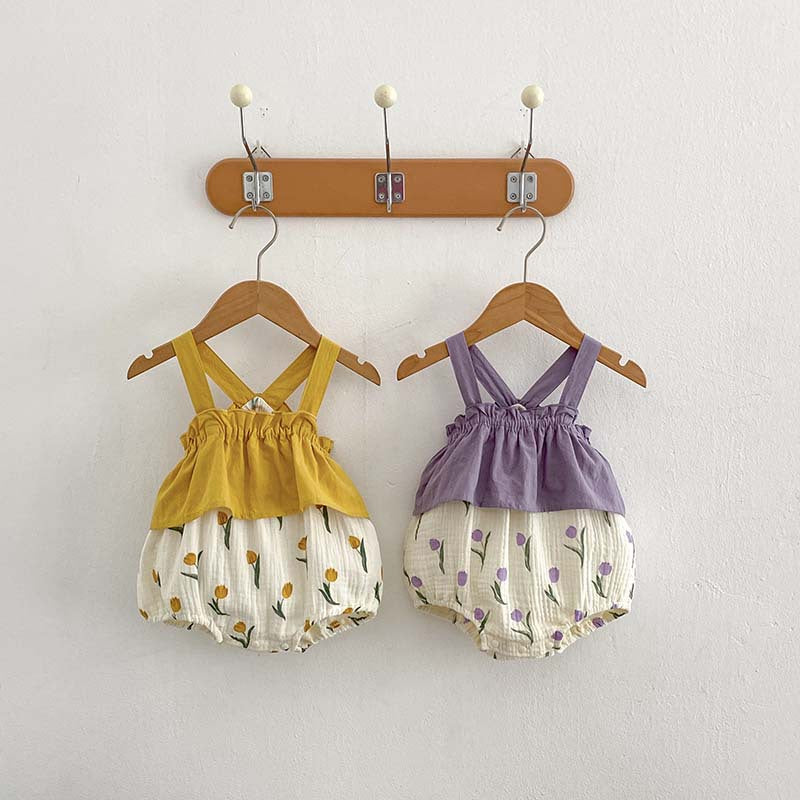 A cute baby girl wearing a sleeveless summer dress with a flowers pattern in purple and yellow colors, perfect for warm weather.