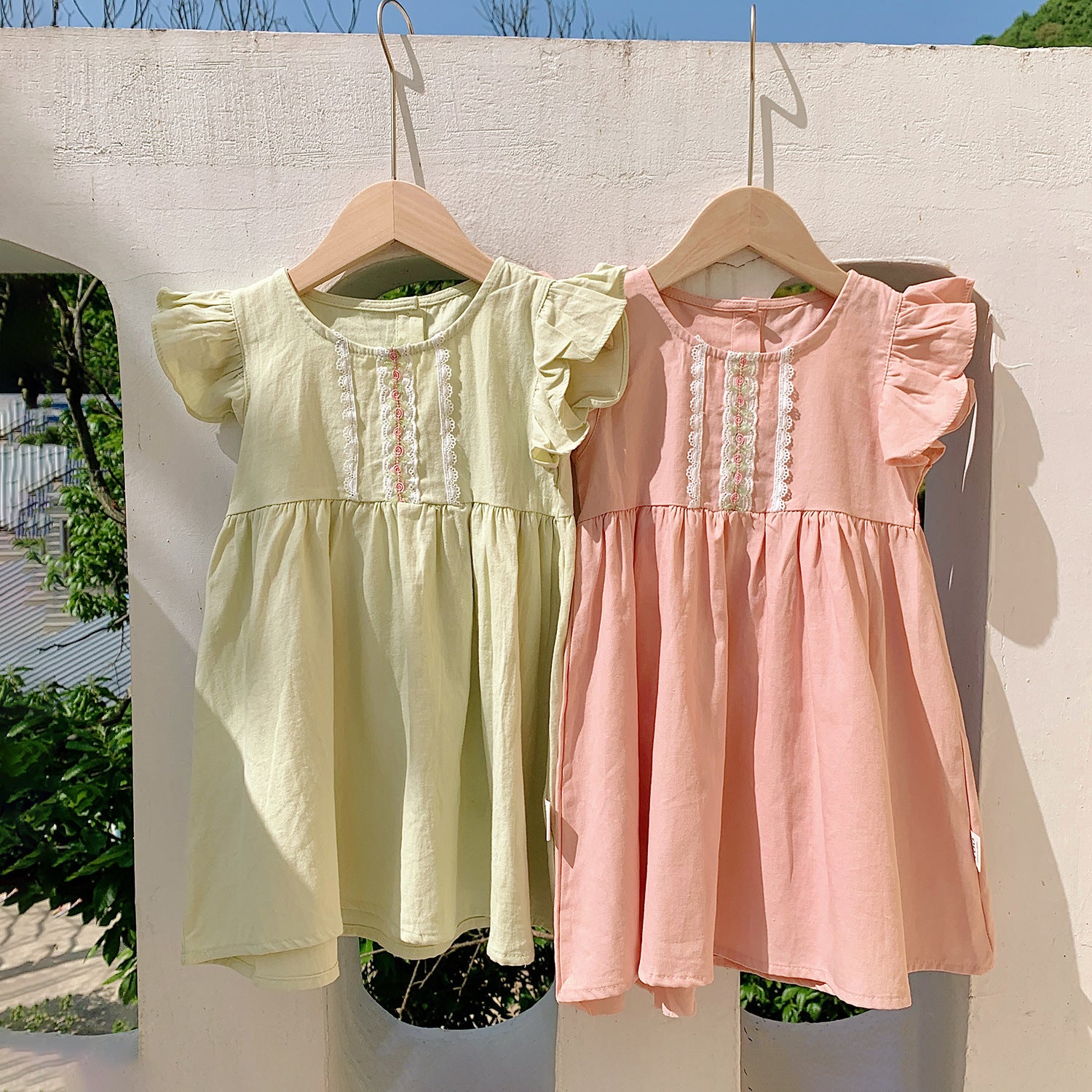 A stylish summer dress for girls featuring fly sleeves and a lace pattern, available in pink and green colors.