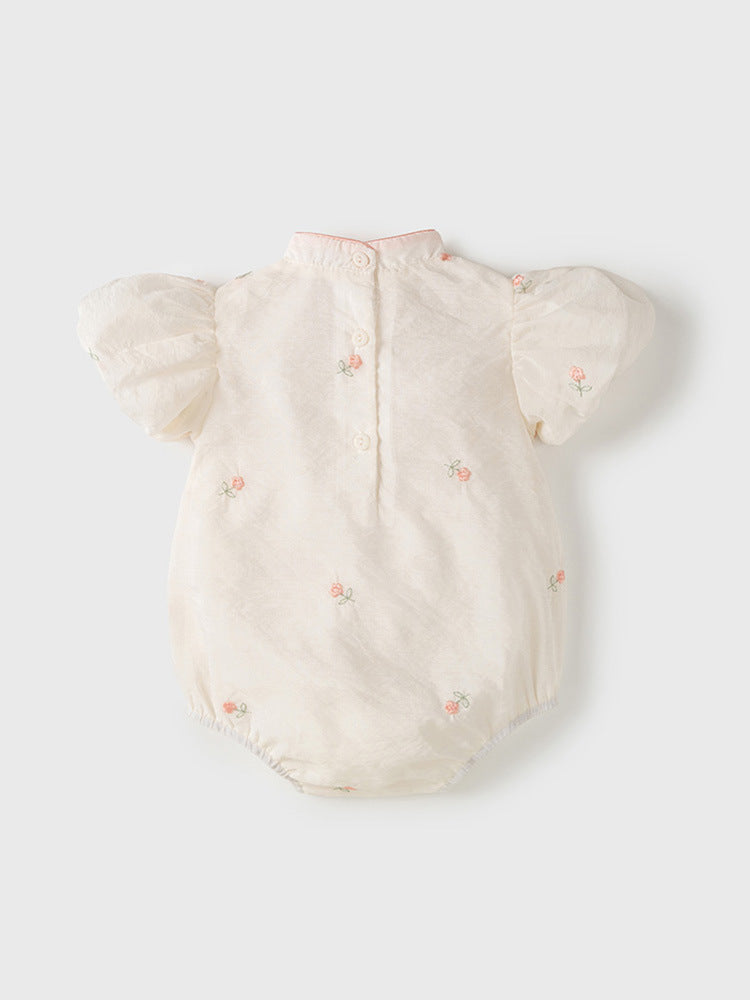 A baby girl wearing a light floral pattern short sleeves stand outfit in apricot color, perfect for summer.