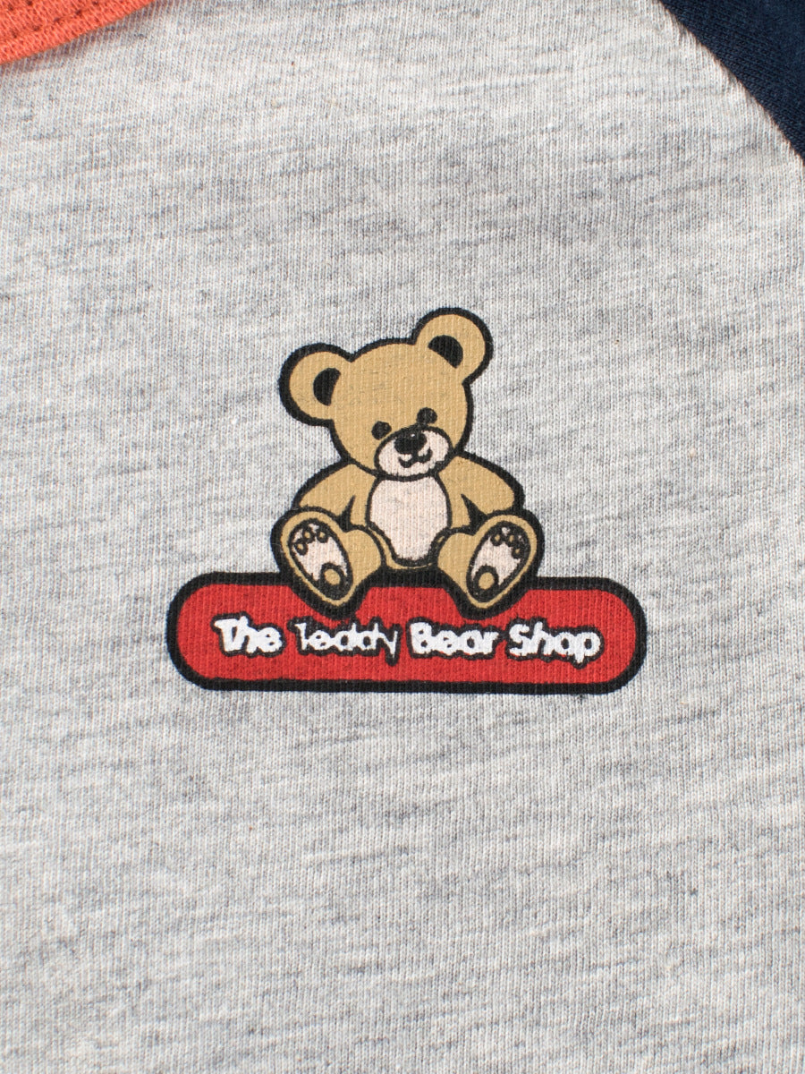 A grey girls' t-shirt featuring a cute teddy bear logo, made from soft cotton, perfect for summer wear.