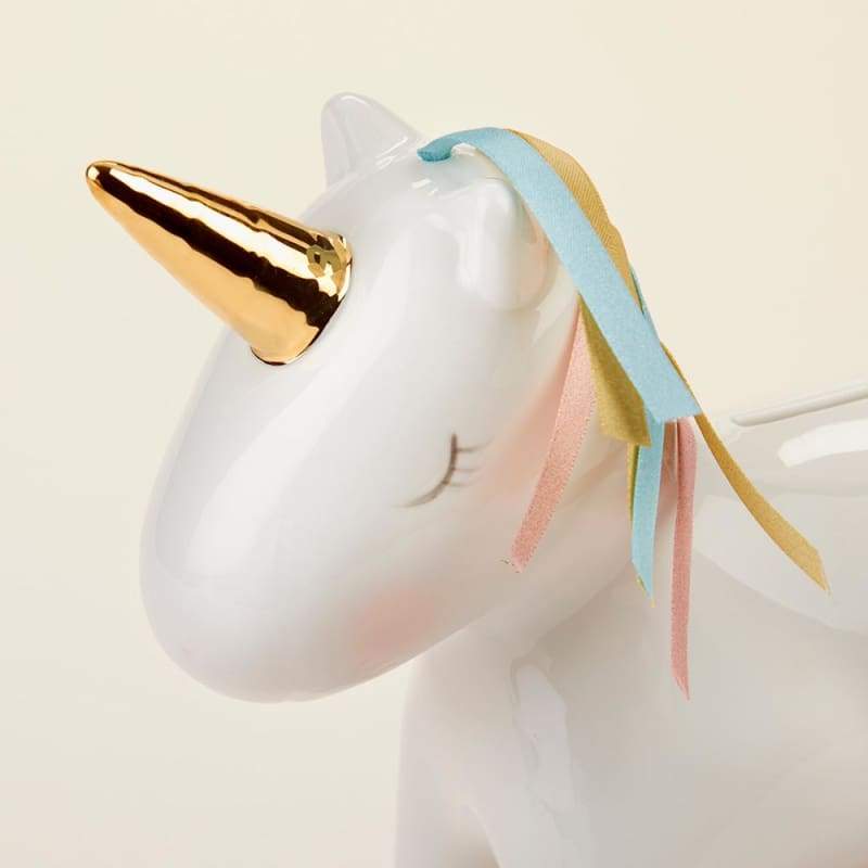 A beautifully crafted white porcelain unicorn bank with a gold foil horn and hooves, featuring a colorful mane and tail made of pink, aqua, and gold ribbons.