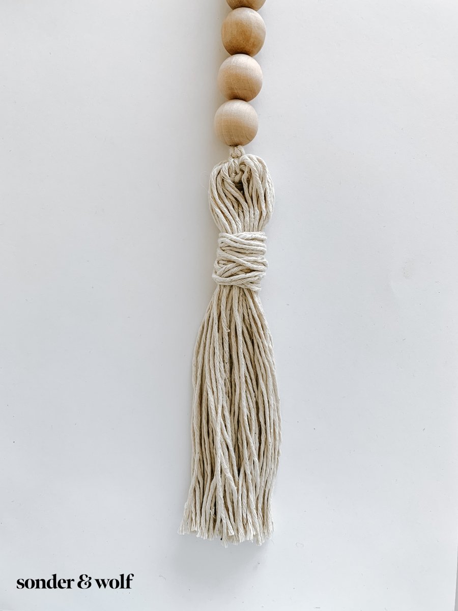 Handmade variated wood bead garland featuring cotton tassels, perfect for home decor.