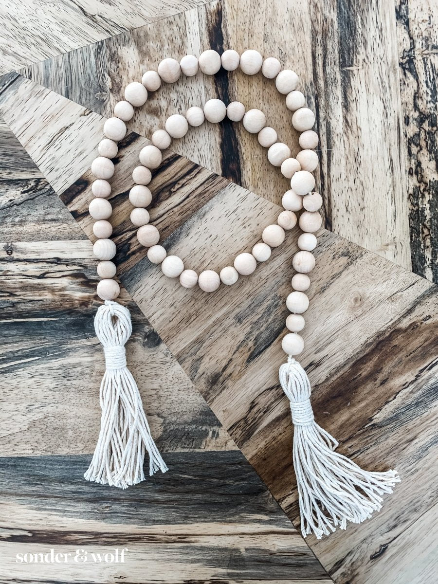 Handmade variated wood bead garland featuring cotton tassels, perfect for home decor.