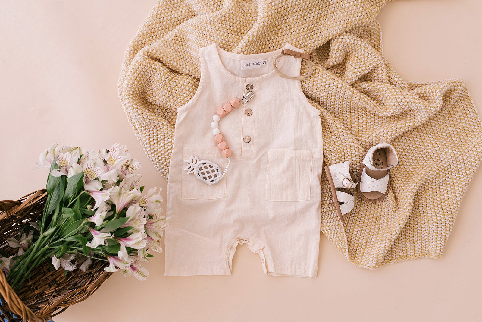 A pure white crop linen romper designed for babies, featuring diaper snaps and a stylish, breathable fabric.