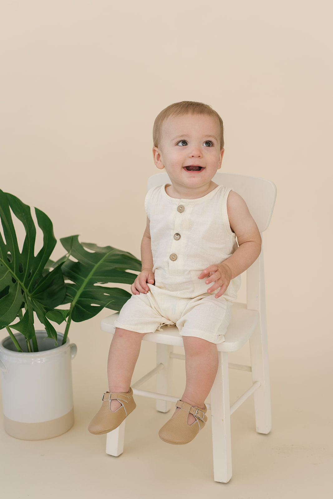 A pure white crop linen romper designed for babies, featuring diaper snaps and a stylish, breathable fabric.