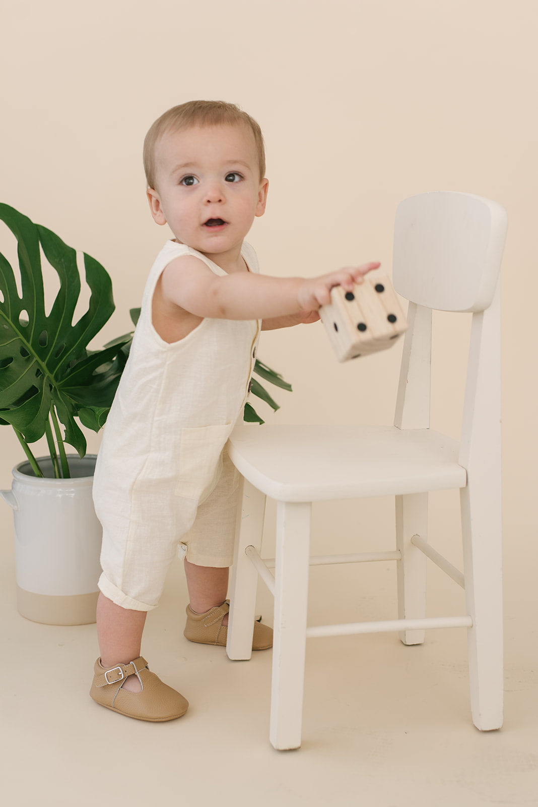 A pure white crop linen romper designed for babies, featuring diaper snaps and a stylish, breathable fabric.