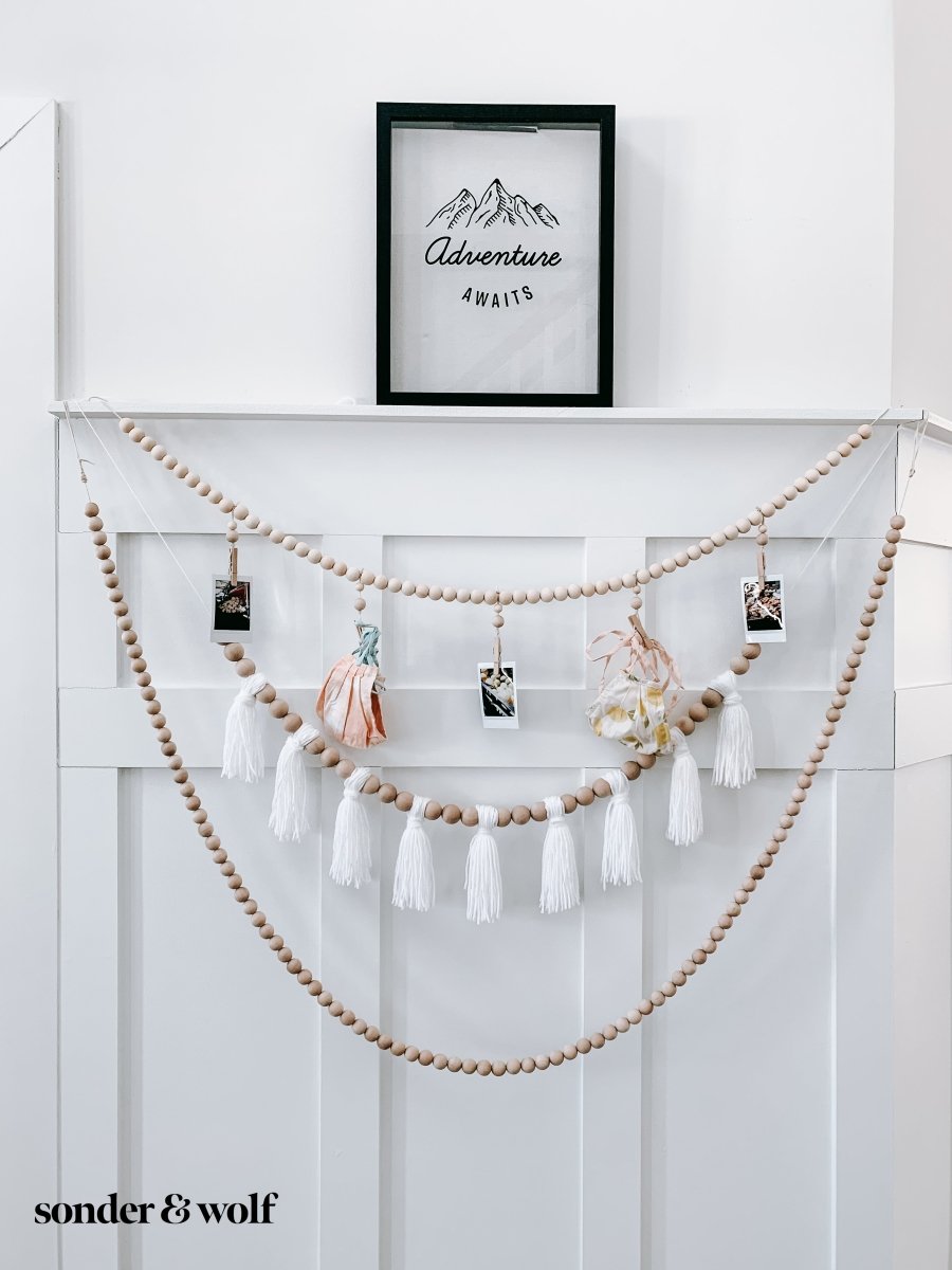 Wood Bead Garland featuring clothespins for hanging photos and masks, showcasing light unfinished wood beads and decorative loops.