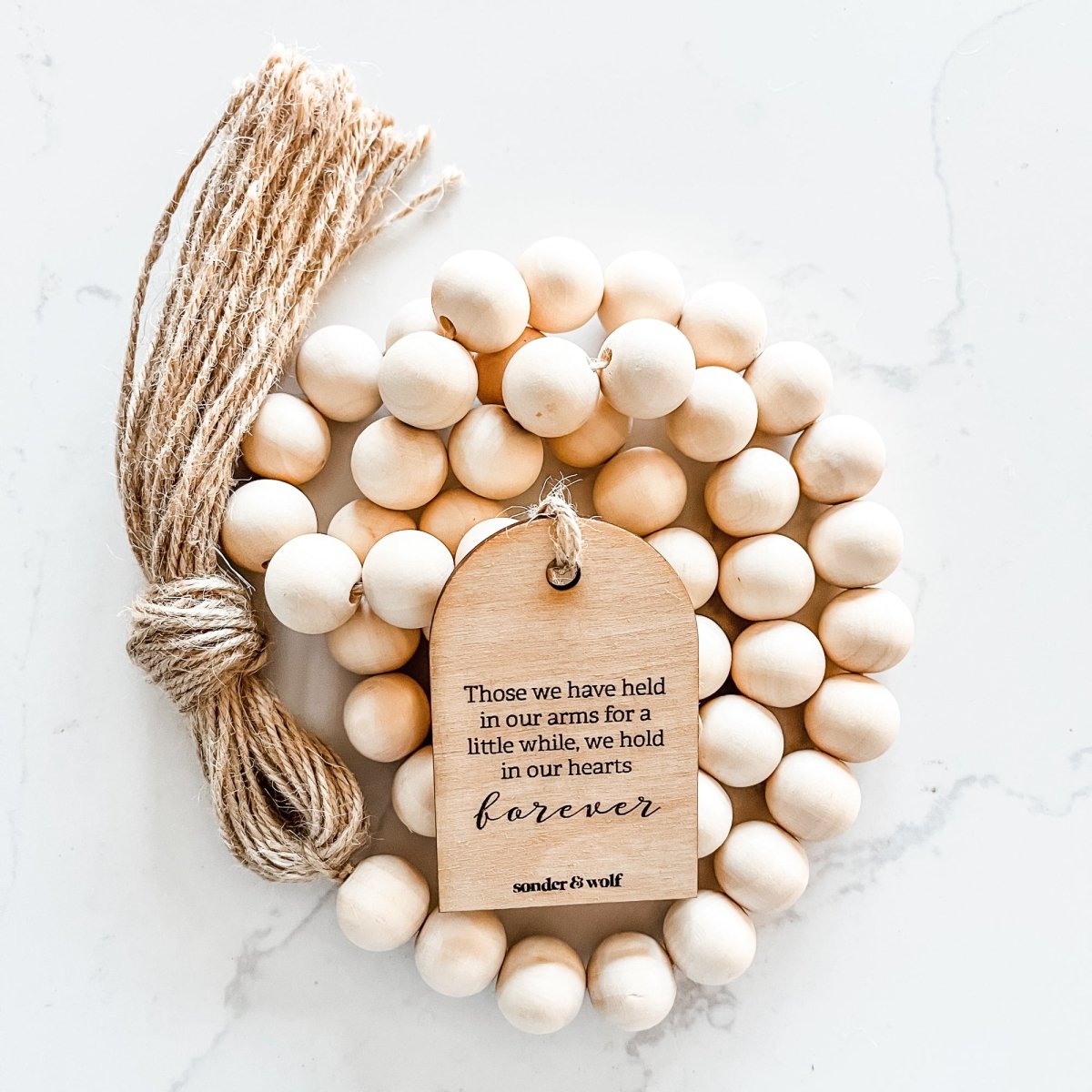 Natural wood bead garland with a heartfelt tag, featuring a jute tassel, perfect for home decor.