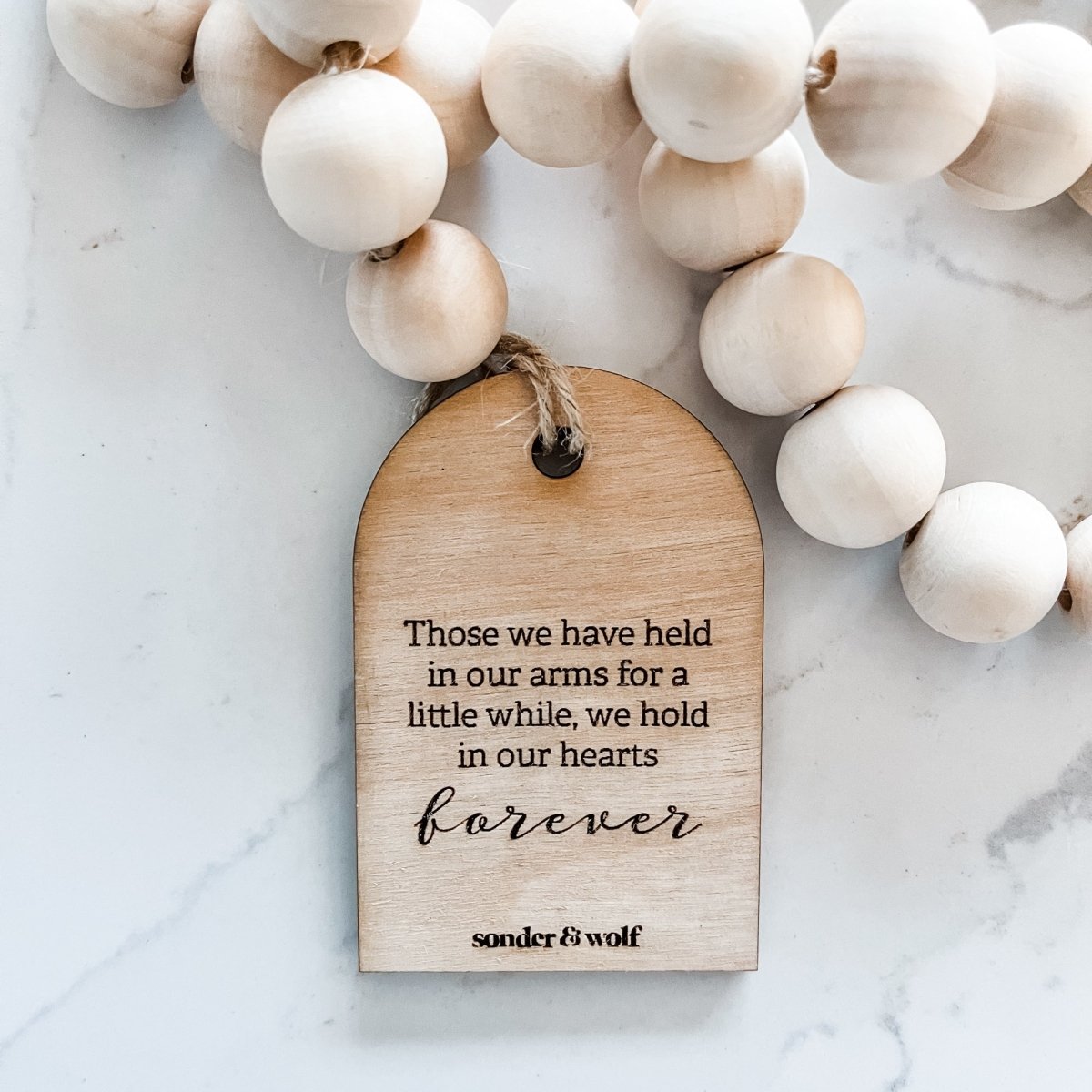 Natural wood bead garland with a heartfelt tag, featuring a jute tassel, perfect for home decor.