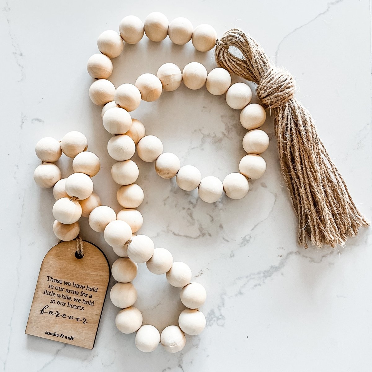 Natural wood bead garland with a heartfelt tag, featuring a jute tassel, perfect for home decor.