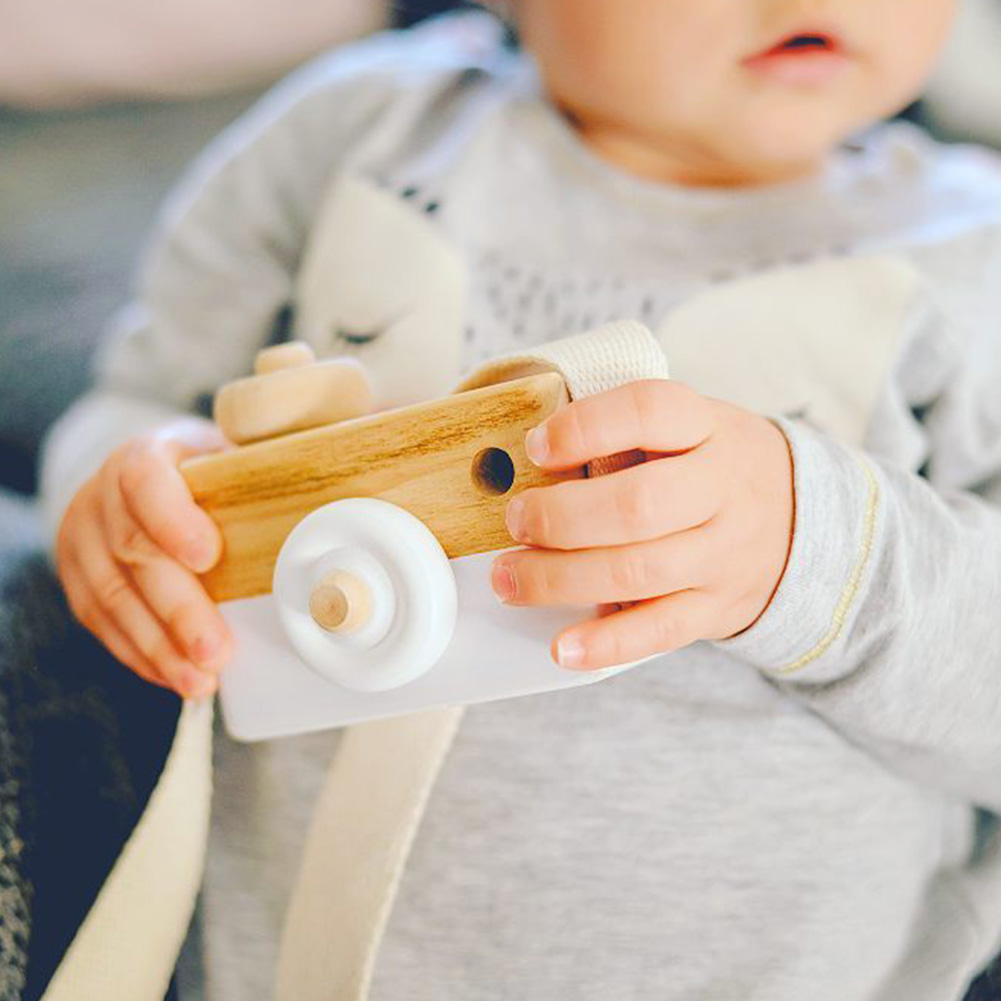 Baby holding wooden toy camera.