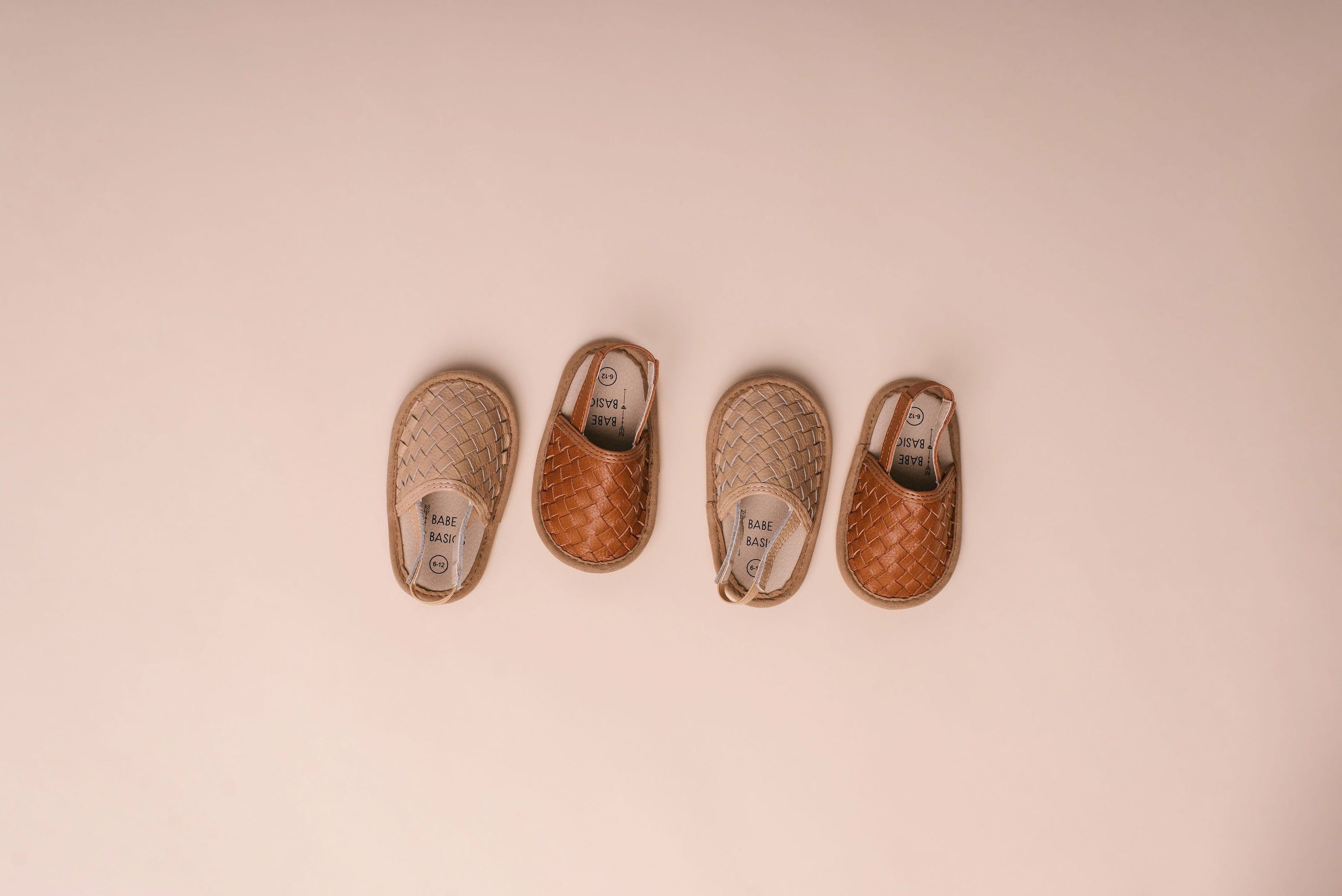 A pair of stylish woven leather sandals in Tawny and Latte colors, designed for toddlers with soft soles and ankle strap buckles.