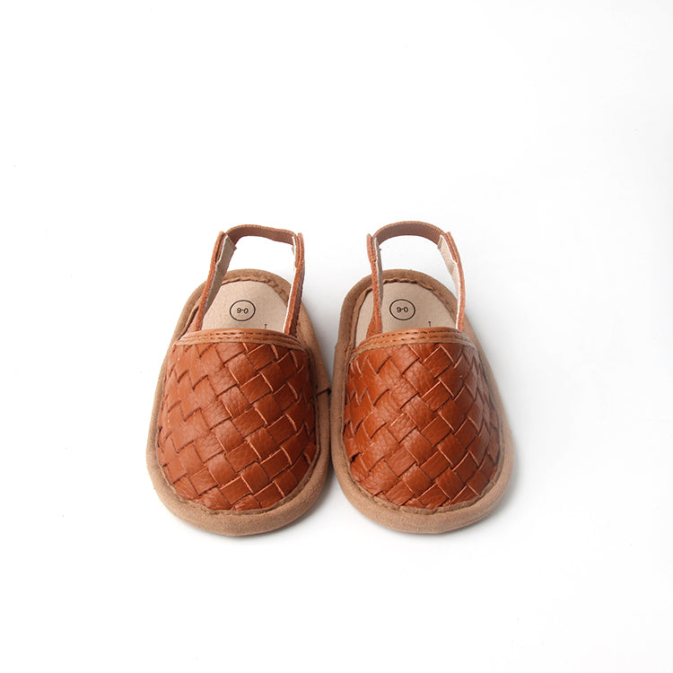 A pair of stylish woven leather sandals in Tawny and Latte colors, designed for toddlers with soft soles and ankle strap buckles.