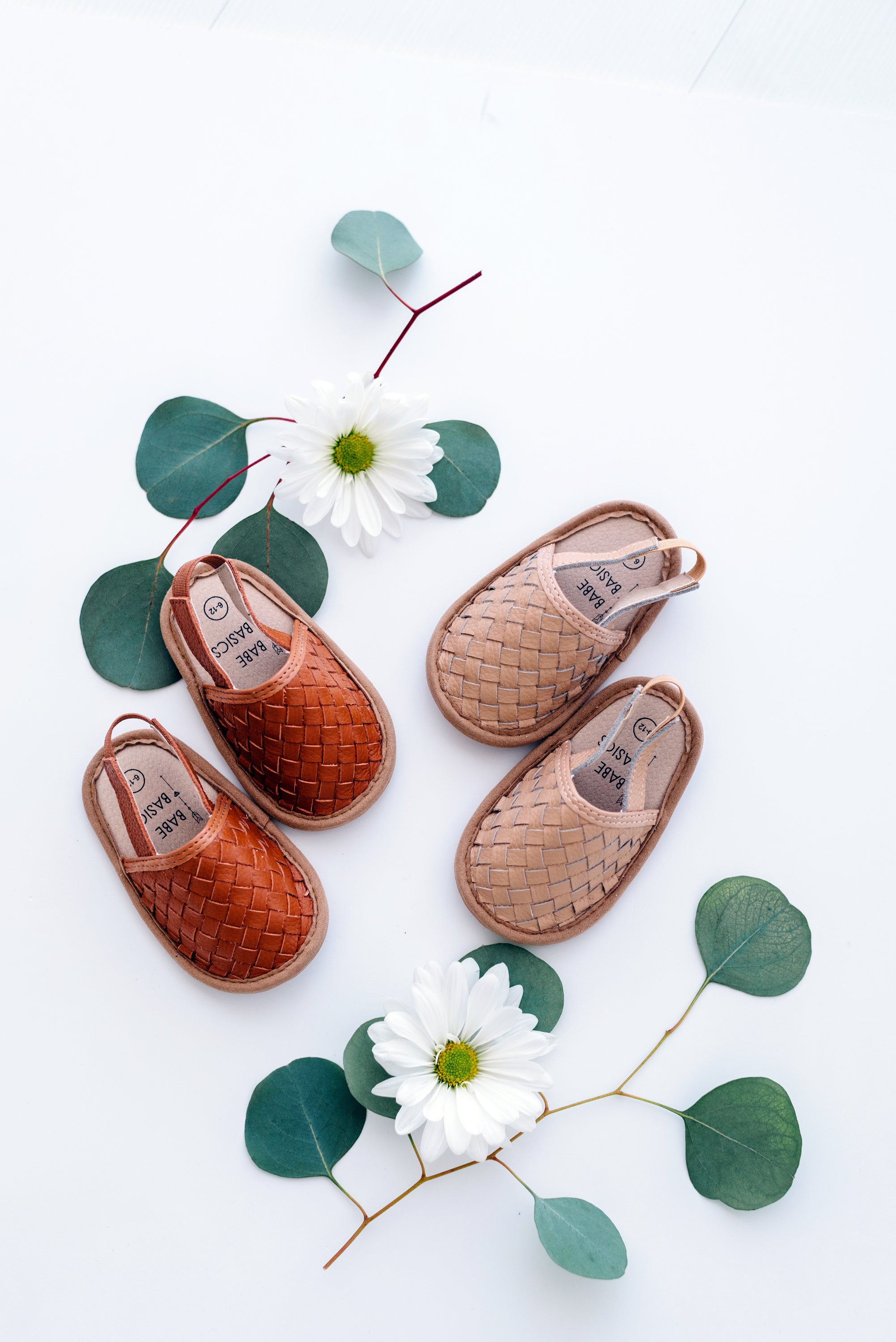 A pair of stylish woven leather sandals in Tawny and Latte colors, designed for toddlers with soft soles and ankle strap buckles.