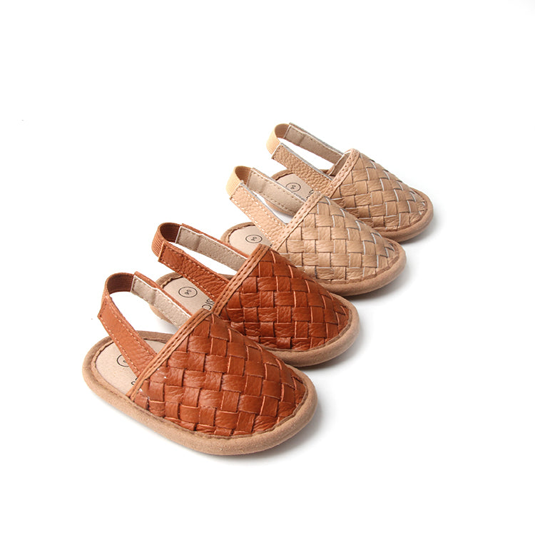 A pair of stylish woven leather sandals in Tawny and Latte colors, designed for toddlers with soft soles and ankle strap buckles.