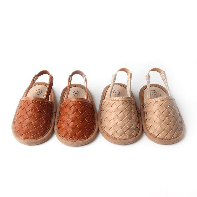 A pair of stylish woven leather sandals in Tawny and Latte colors, designed for toddlers with soft soles and ankle strap buckles.