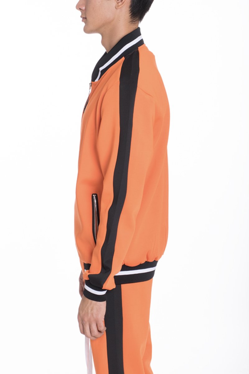 RALLY TRACK SET in vibrant orange featuring a tug-free zipper, ribbed elastic waist, and cuffs, perfect for casual wear and workouts.