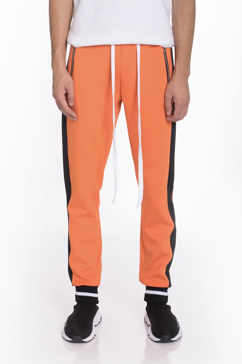 RALLY TRACK SET in vibrant orange featuring a tug-free zipper, ribbed elastic waist, and cuffs, perfect for casual wear and workouts.