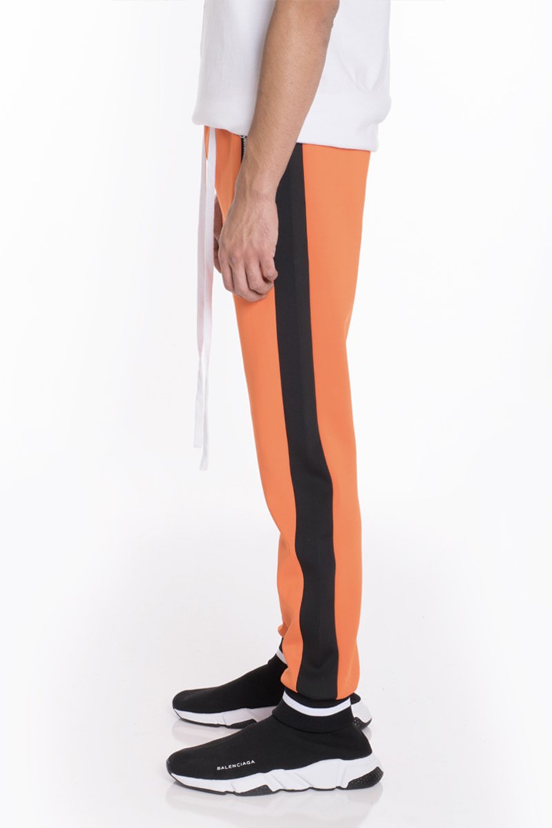 RALLY TRACK SET in vibrant orange featuring a tug-free zipper, ribbed elastic waist, and cuffs, perfect for casual wear and workouts.