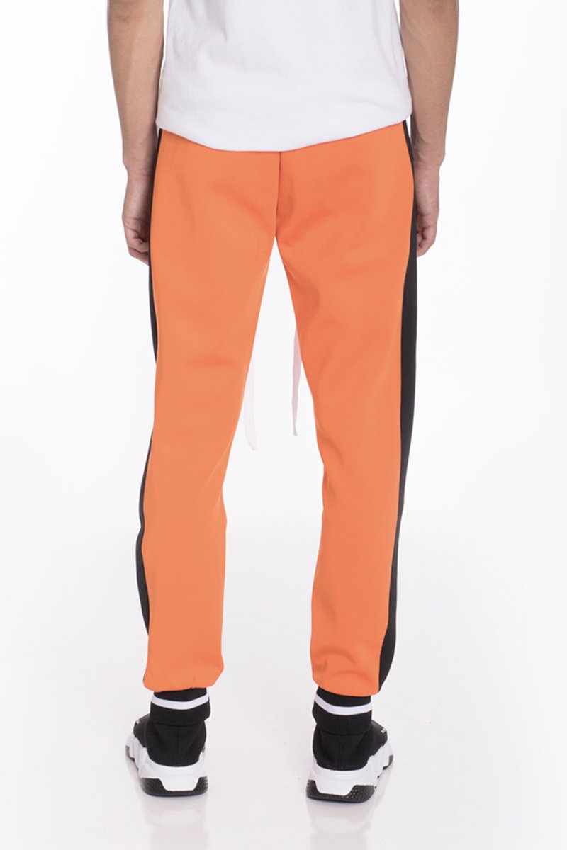 RALLY TRACK SET in vibrant orange featuring a tug-free zipper, ribbed elastic waist, and cuffs, perfect for casual wear and workouts.