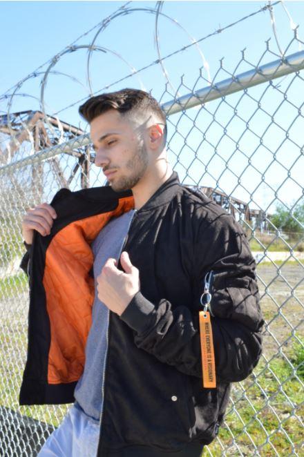 A stylish faux suede bomber jacket featuring ribbed cuffs, neckline, and hem, with two side pockets and a utility pocket on the left sleeve.