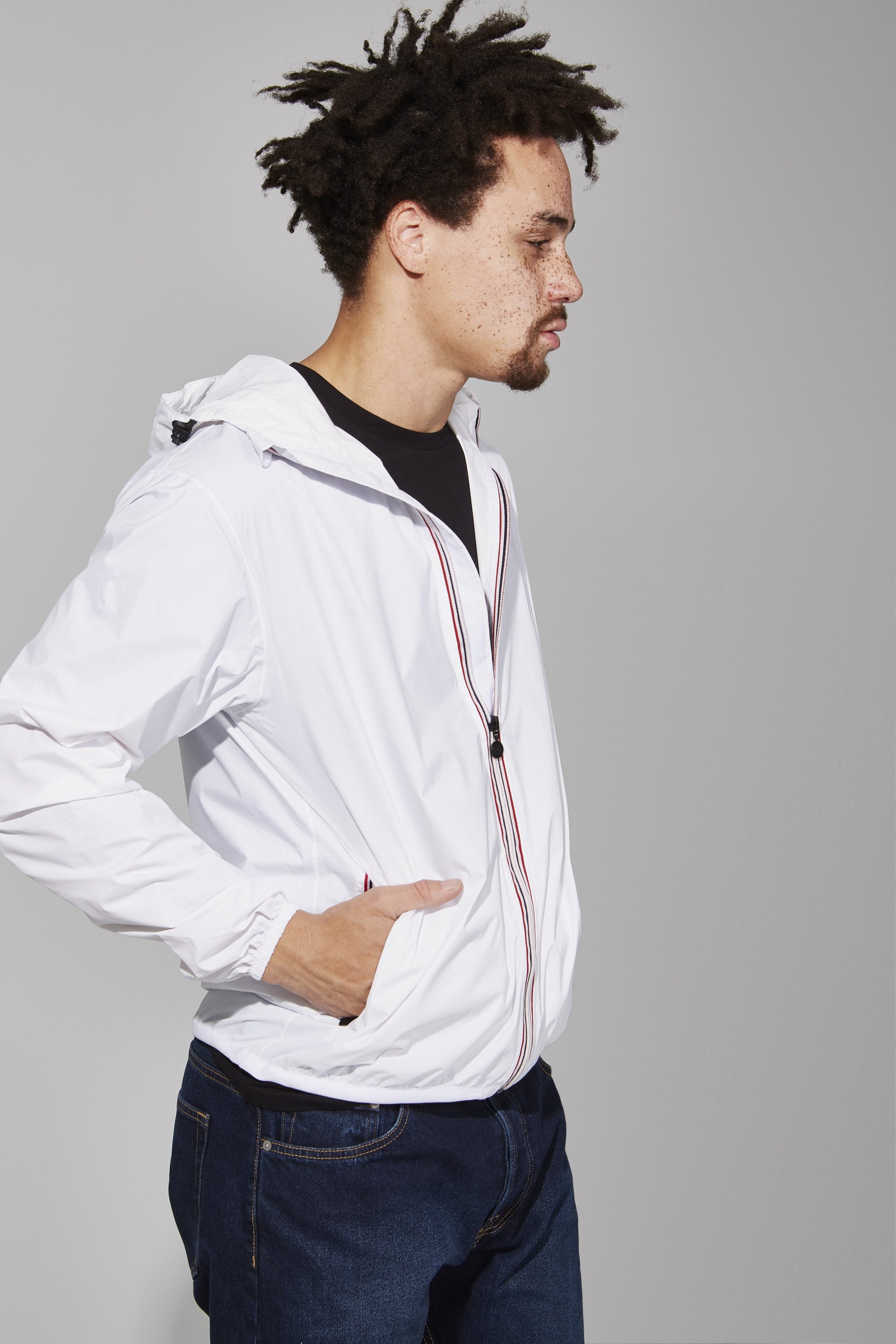 Men's white full zip packable rain jacket displayed on a mannequin, showcasing its sleek design and packable feature.