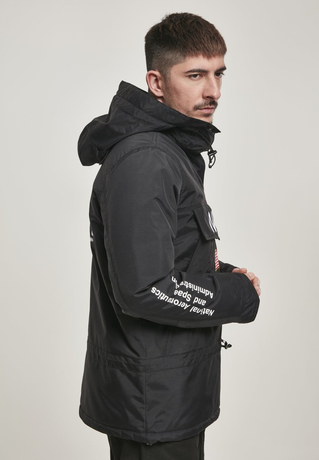 A stylish black windbreaker featuring NASA branding and a USA flag patch, designed with multiple pockets and a unique adjustable hood.