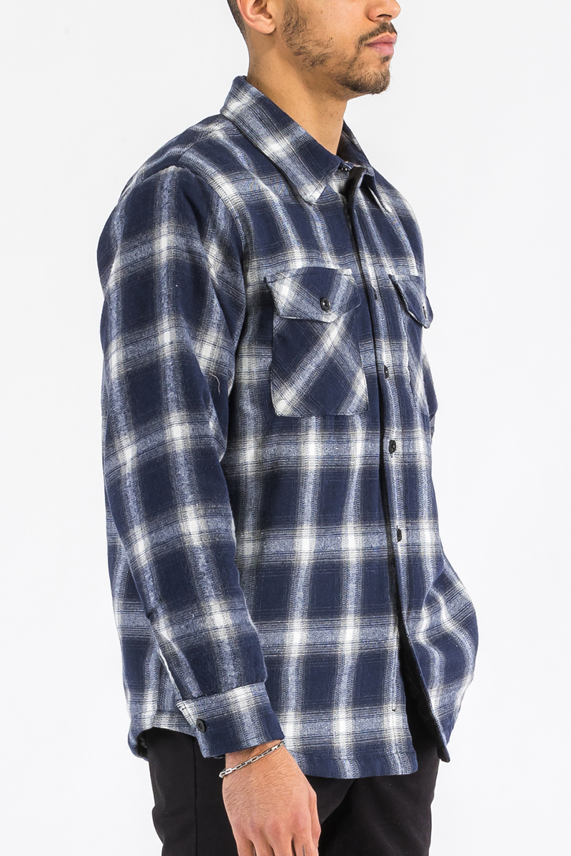 A stylish quilted flannel shirt featuring a button closure, cozy lining, and side pockets, perfect for layering and casual wear.