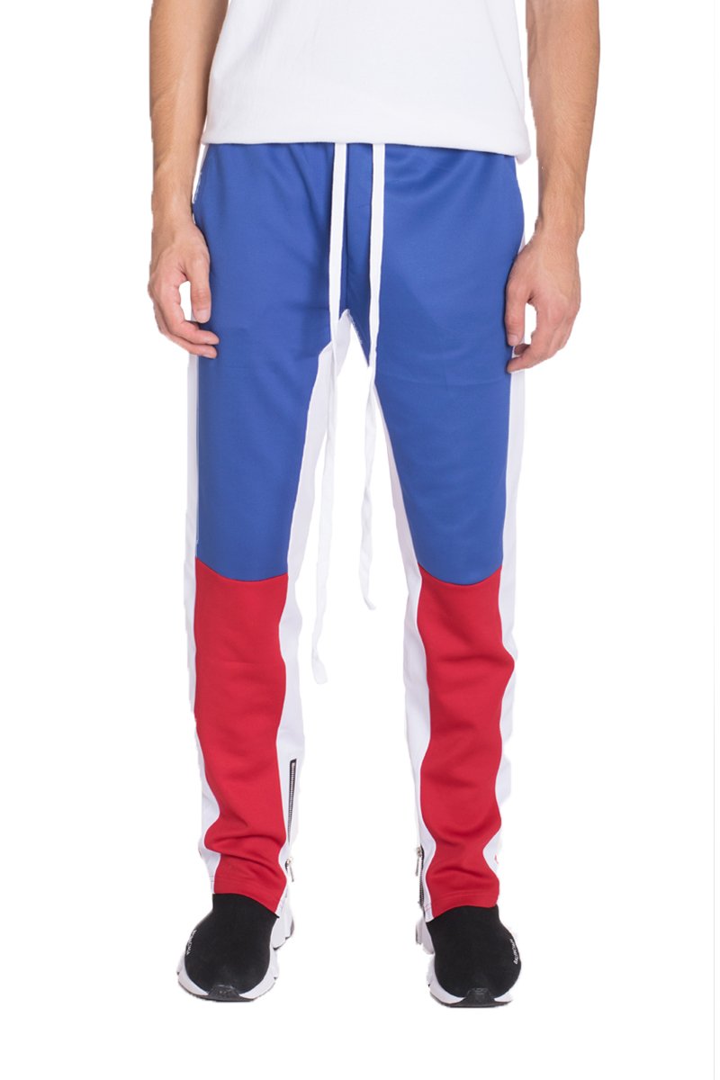 A pair of stylish color block track pants featuring a regular fit, standard pockets, and hidden ankle zippers, displayed on a model.